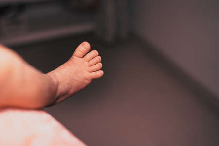 Close-up of unrecognizable cute baby foot while lying in bed, innocence conceptの写真素材