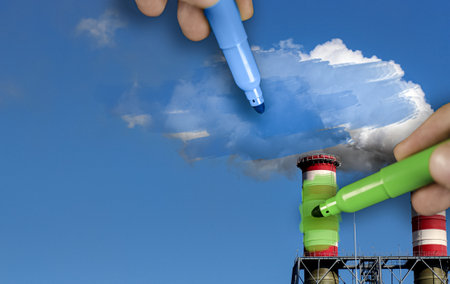 Hands painting blue and green pollution from a chimneyの写真素材