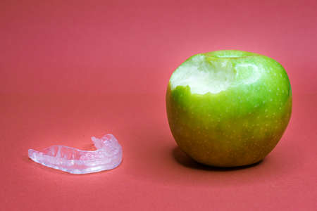 Green apple with bite and a dental splintの写真素材