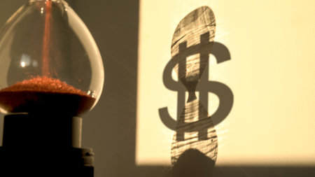 hourglass with shadow of a dollar sign on the background