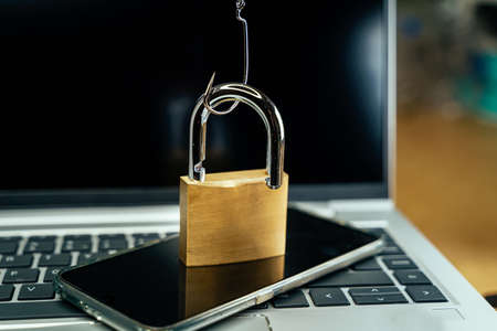 Fishhook opening a padlock over a laptopの写真素材