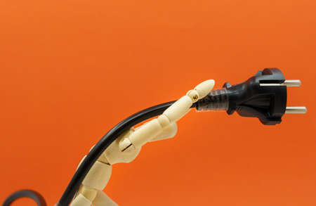 wooden dummy holding an AC polkug and cable as a burden on his shoulders. Concept of rising electricity pricesの写真素材