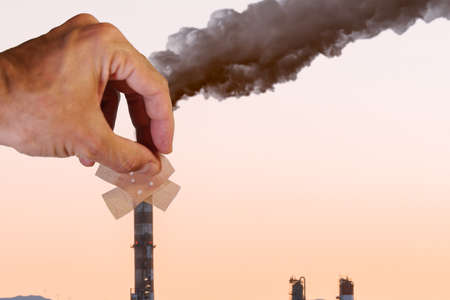 hand putting a plaster on a smoke stackの写真素材