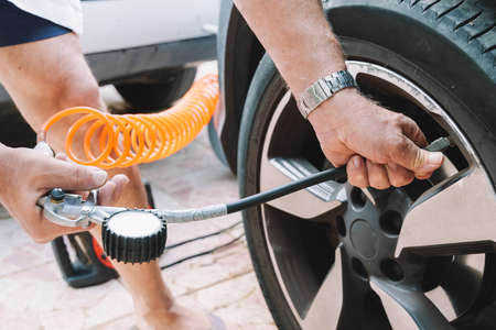 Close up of a mechanic inflating a car tireの写真素材