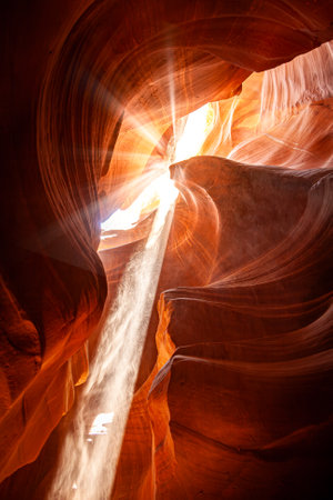 Noon in a red-orange Antelope Canyon. A thin ray of sunlight illuminates the sandy bottom of the canyonの写真素材