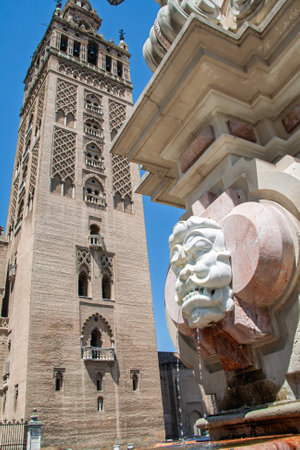 Giralda, the bell tower of seville cathedral, looming over a fountainの写真素材