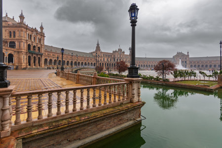 Plaza de espana in seville reflecting on the water under a cloudy skyの写真素材