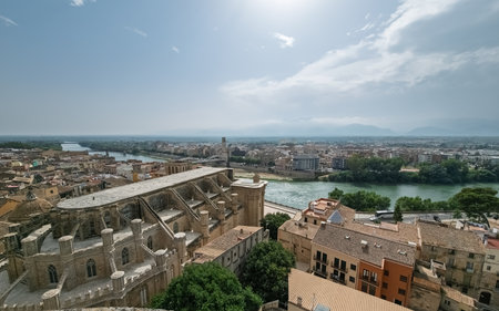 Panoramic view of Tortosa, Ebro River flowing through city center and old cathedral on sunny dayの写真素材