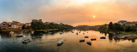 San Vicente de la Barquera reflecting on the calm water at sunriseの写真素材