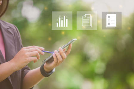 Woman hand and pen use smartphone for business and social networks with trendy icons, stock trading, email, checklist.の写真素材