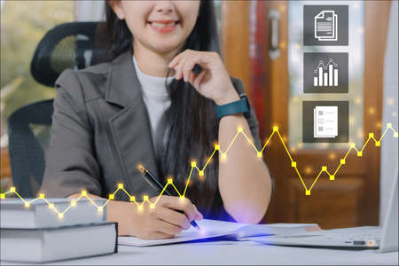 business woman in a suit working on a laptop and taking notes and check the crypto stock price tableの写真素材