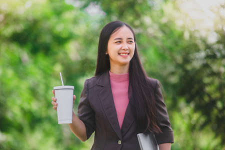 business woman Standing drink coffee in the park beside the townの写真素材