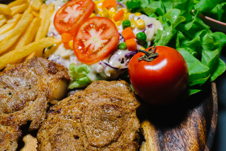 Grilled steak and lettuce, French fries on wooden plateの写真素材