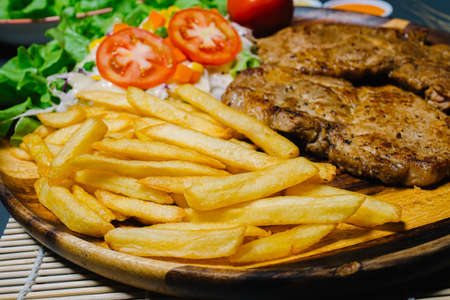 Grilled steak and lettuce, French fries on wooden plateの写真素材