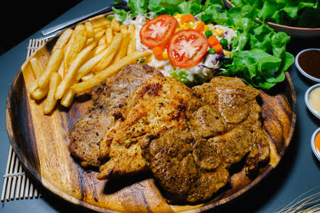 Grilled steak and lettuce, French fries on wooden plateの写真素材