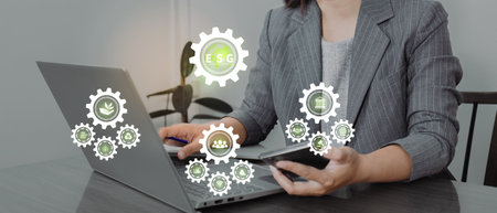 Businesswoman hand using smart phone and laptop computer with gear wheel icon on screenの写真素材