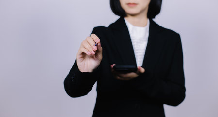 Business woman using smart phone on gray background. Focus on hand.の写真素材