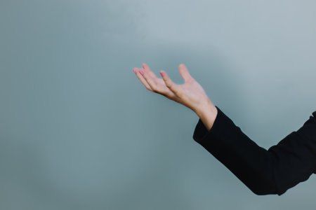 Close up of businesswoman hand showing something on grey background with copy spaceの写真素材