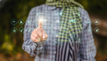 A close-up shot of a person, likely a farmer or agricultural professional, wearing a traditional plaid shirt and scarf, pointing towards a futuristic holographic diagram. The diagram visually represents the integration of Smart Agriculture technologies with ESG (Environmental, Social, and Governance) principles. Various icons within the hologram symbolize elements like drones, sensors, tractors, data analytics, and sustainable practices, highlighting innovation and responsible farming. The blurred natural background suggests an outdoor, rural setting.の写真素材