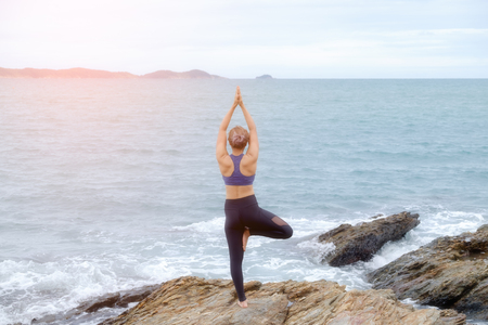 The woman practicing yoga on the beach at sunset.の写真素材