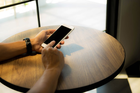 Close up of a man using mobile smart phone on the table