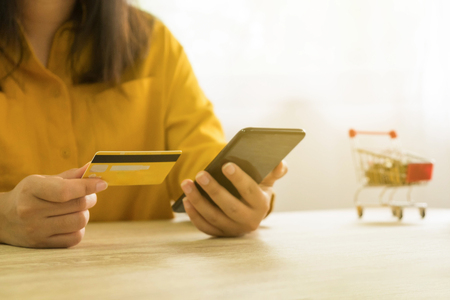 Woman holding credit card and using smartphone for shopping onlineの写真素材