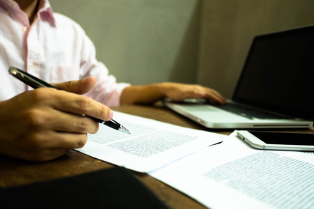 Businessman working at office with laptop and documents on the table, Businessman holding pens and papers taking notes in documents on the table.の写真素材