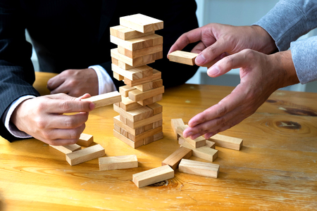 Businessmen picking domino blocks to fill the missing dominos and protect domino to fail. Growing business concept.の写真素材