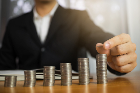 Businessman picks coins on the table, counts money . Business concept.の写真素材