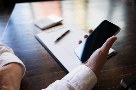 Close up of a man using mobile smart phone on the table.の写真素材