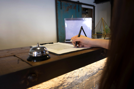Close up of women putting signing and filling up form at hotel reception.の写真素材
