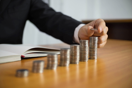 Businessman picks coins on the table, counts money . Business concept.の写真素材