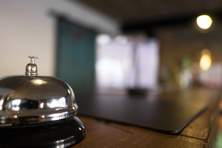 Service bell locating at reception. Silver call bell on table, receptionists on background.の写真素材