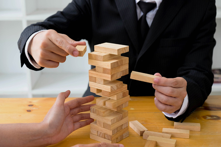 Businessmen picking wood blocks to fill the missing wood blocks and protect wood blocks to fail. Growing business concept.の写真素材
