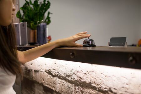 Close up women call hotel reception on counter desk with finger push a bell in lobby hotel. hotel concept.の写真素材