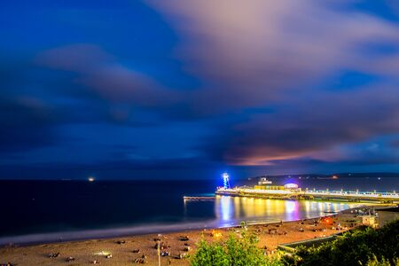 Bournemouth Pier in the night time with many tourist enjoying their time on a beach.の写真素材
