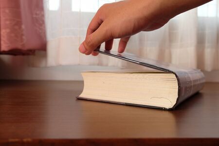 Close up of Thick old book that place on a table near to the window and curtain with blurred...