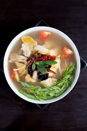 spicy chicken and herbal soup on wooden table