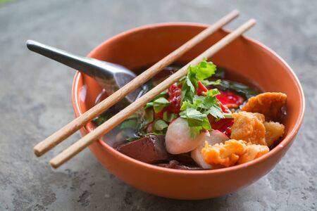 noodles with fishball and vegetable with red sauce on table