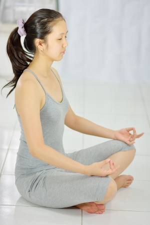 young asian woman practicing yoga in pose of lotusの写真素材