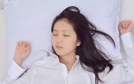 woman too tired fall a sleep on her bed の写真素材