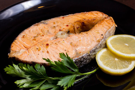 Grilled salmon steak on a black plateの写真素材