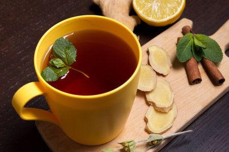 Cup of healthy ginger tea with mint and lemon on a wooden boardの写真素材