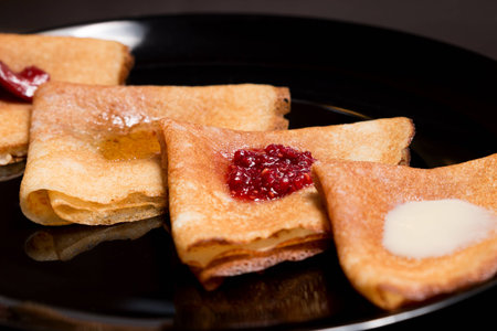 Pancakes with strawberry jam, raspberry jam, sour cream and honeyの写真素材