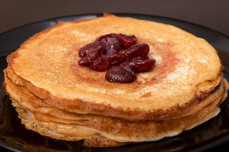 Pancakes with strawberry jam on a black plateの写真素材
