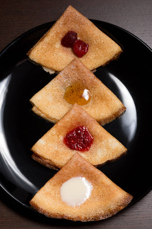 Pancakes with strawberry jam, raspberry jam, sour cream and honeyの写真素材