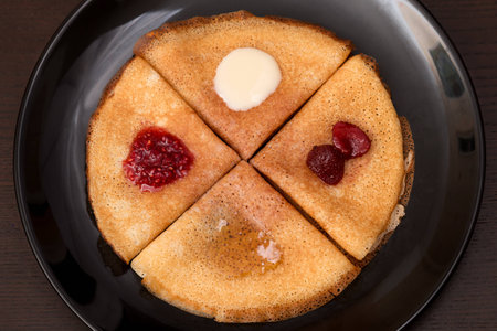 Pancakes with strawberry jam, raspberry jam, sour cream and honeyの写真素材