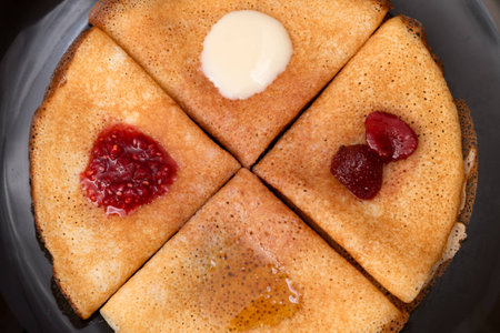 Pancakes with strawberry jam, raspberry jam, sour cream and honeyの写真素材