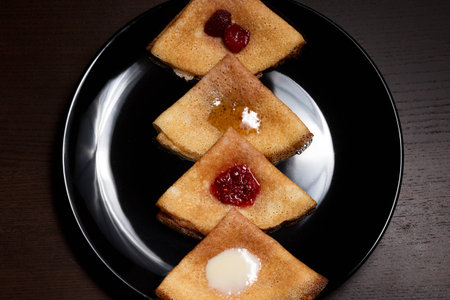 Pancakes with strawberry jam, raspberry jam, sour cream and honeyの写真素材
