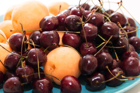 Fresh apricots and cherry on a plateの写真素材
